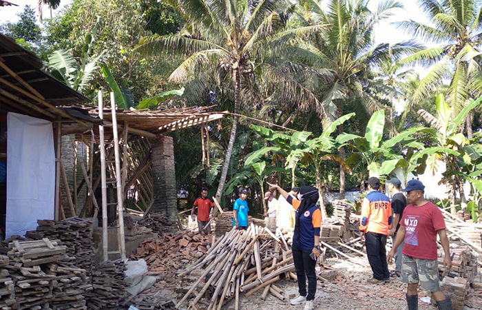 GOTONG ROYONG : Warga bersama petugas gabungan membersihkan sisa material bangunan pasca terjadi gempa.