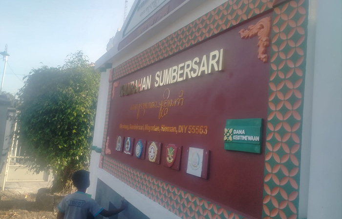 DARI DANAIS: Seorang bocah melihat papan penanda Keistimewaan Kalurahan Sumbersari, Moyudan yang dibangun menggunakan danais