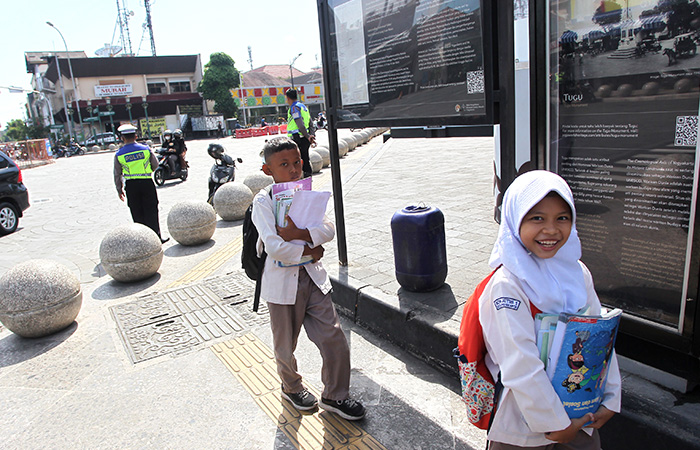 TUNTUT ILMU : Dua pelajar sekolah dasar berjalan pulang melintas di kawasan Tugu Jogja, Kamis (13/7/23). ORI Perwakilan DIJ menemukan kasus menumpang Kartu Keluarga (KK) dalam proses PPDB tahun 2023