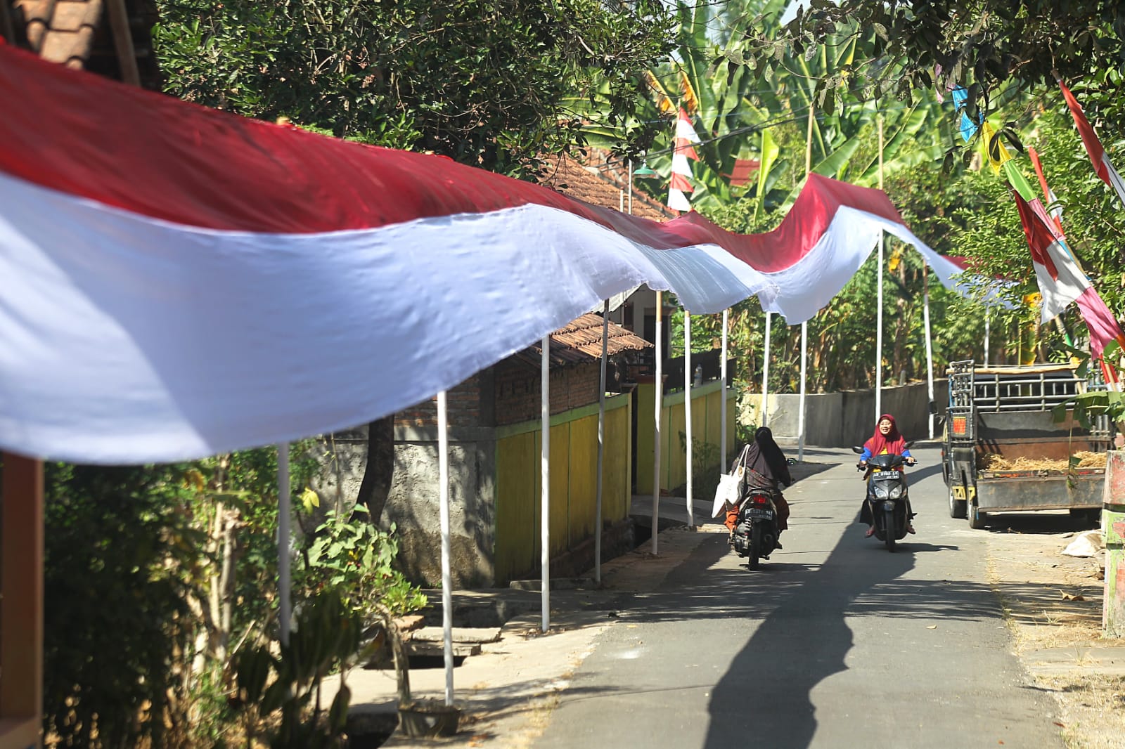 MERDEKA: Warga melintas di dekat bendera Merah-Putih di Dusun Karang, Kelurahan Jatisarono, Kapanewon Nanggulan, Kulon Progo, DIY, Selasa (1/8). (Guntur Aga Tirtana/Radar Jogja)
