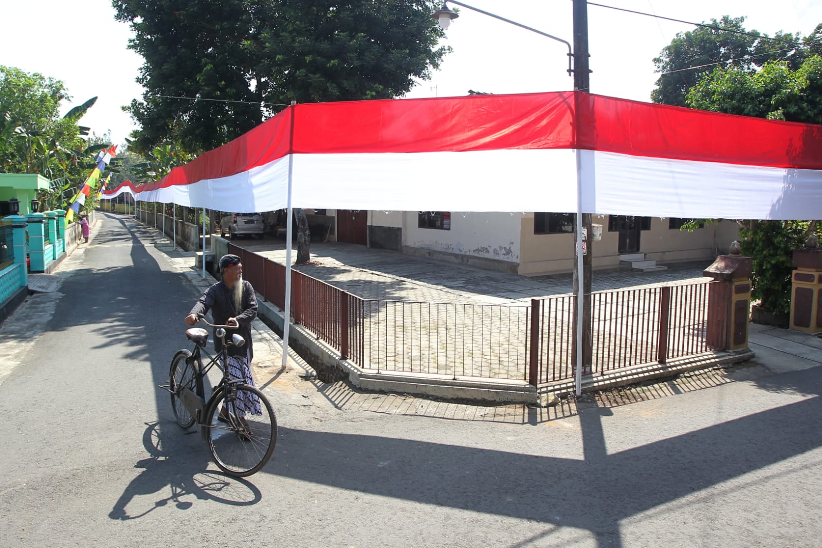 MERDEKA: Warga melintas di dekat bendera Merah-Putih di Dusun Karang, Kelurahan Jatisarono, Kapanewon Nanggulan, Kulon Progo, DIY, Selasa (1/8). (Guntur Aga Tirtana/Radar Jogja)