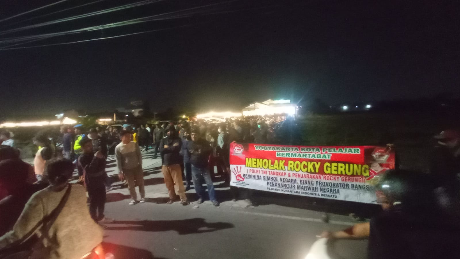 MENOLAK: Warga membentangkan spanduk di sekitar Bento Kopi Godean, Sleman, Rabu malam (2/8/2023). (Radar Jogja)