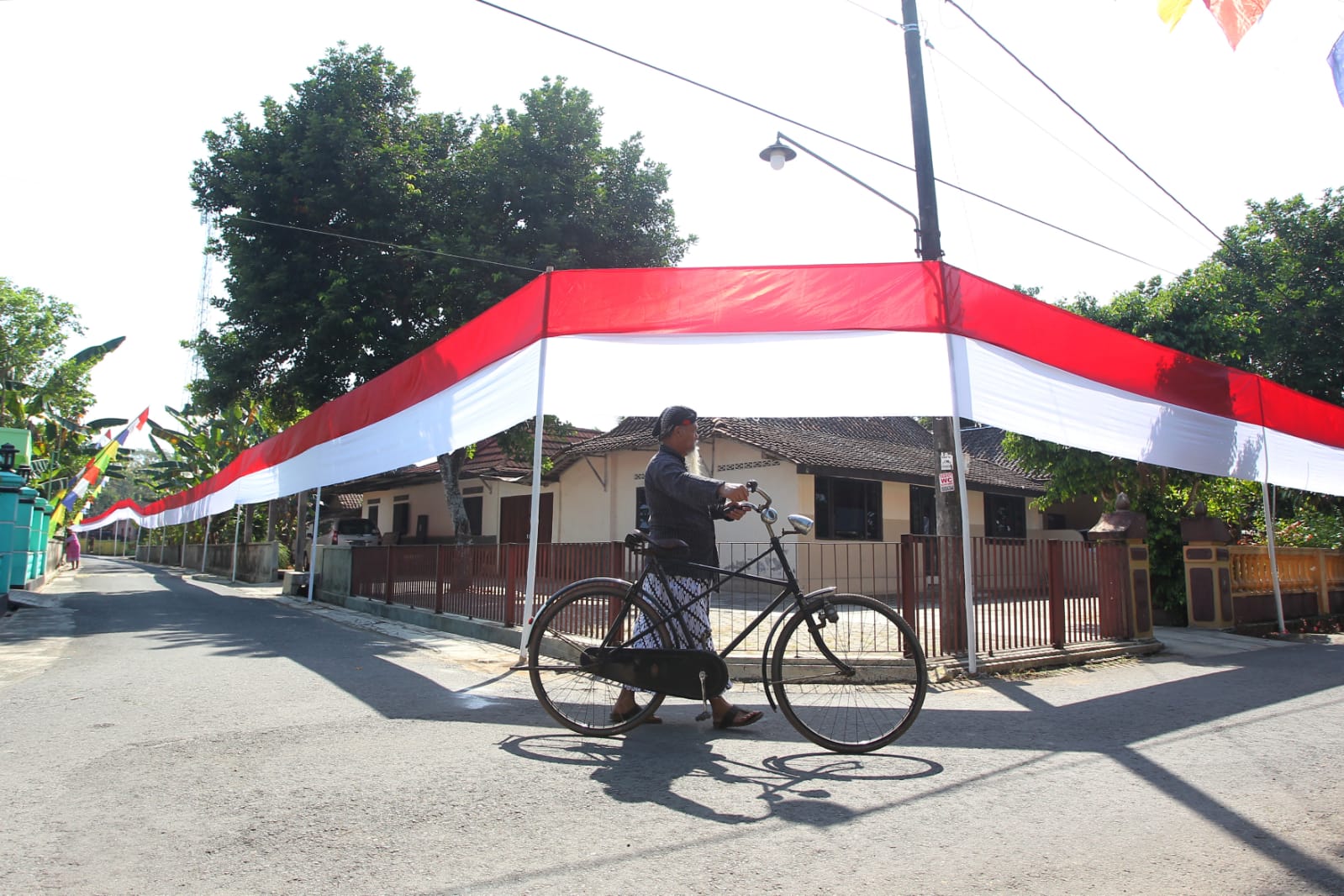 MERAH PUTIH: Warga menaiki sepeda di dekat bendera Merah-Putih di Dusun Karang, Kelurahan Jatisarono, Kapanewon Nanggulan, Kulon Progo, DIY, Selasa (1/8). (Guntur Aga Tirtana/Radar Jogja)
