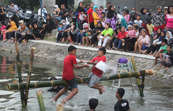 Anak-anak mengikuti lomba gebuk bantal di atas bambu, di Selokan Mataram.