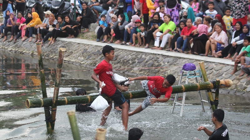 PITULASAN: Dua anak sedang mengikuti lomba gebuk bantal di Selokan Mataram Dusun Mayangan, Trihanggo, Kapanewon Gamping, Sleman, Minggu (6/8). (Guntur Aga Tirtana/Radar Jogja)