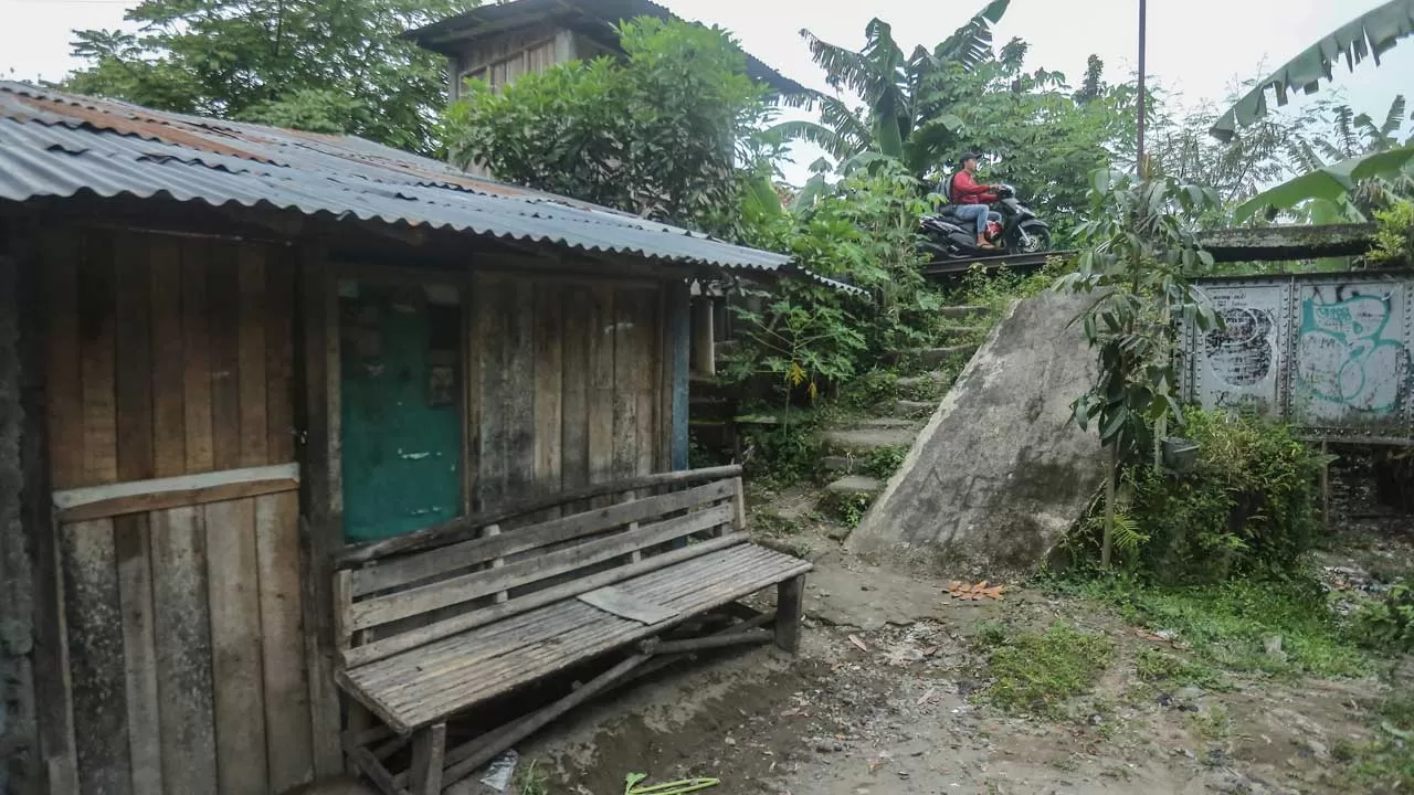 KUMUH: Warga melintas berlatar rumah tidak layak huni di pinggir Sungai Winongo di kawasan Panggungharjo, Sewon. (ELANG KHARISMA DEWANGGA/RADAR JOGJA)