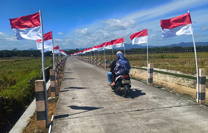 MERDEKA: Bendera merah putih berkibar tertiup angin di jalan penghubung antar desa di Jalan Tumenggungan-Curug sepanjang 1,4 kilometer Jumat (11/8/23).