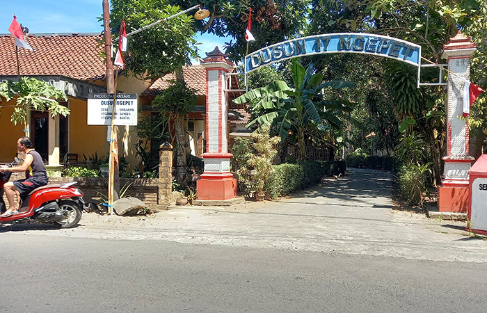UJUNG SELATAN: Seorang warga sedang melintas di depan gapura Pedukuhan Ngepet, lokasinya berada di ujung selatan Bantul, sudah berbatasan langsung dengan Samudera Hindia.