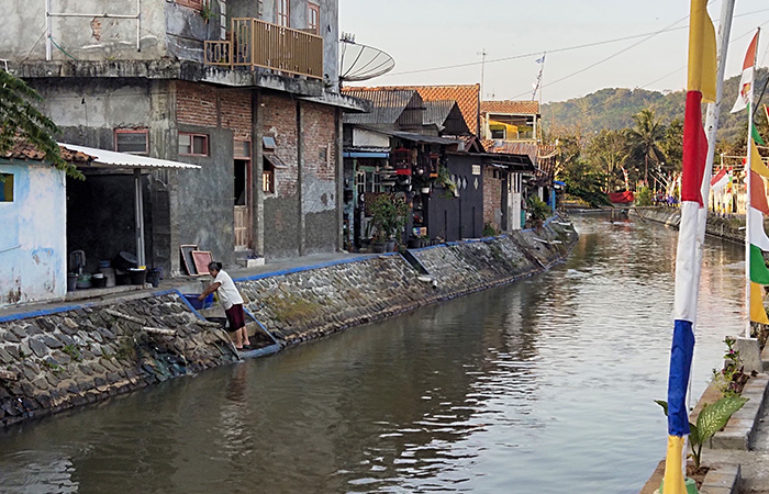 MENCEMATI SUNGAI: Salah seorang warga tengah mencuci pakaian di bantaran Sungai Kedungputri, Minggu (20/8/23).