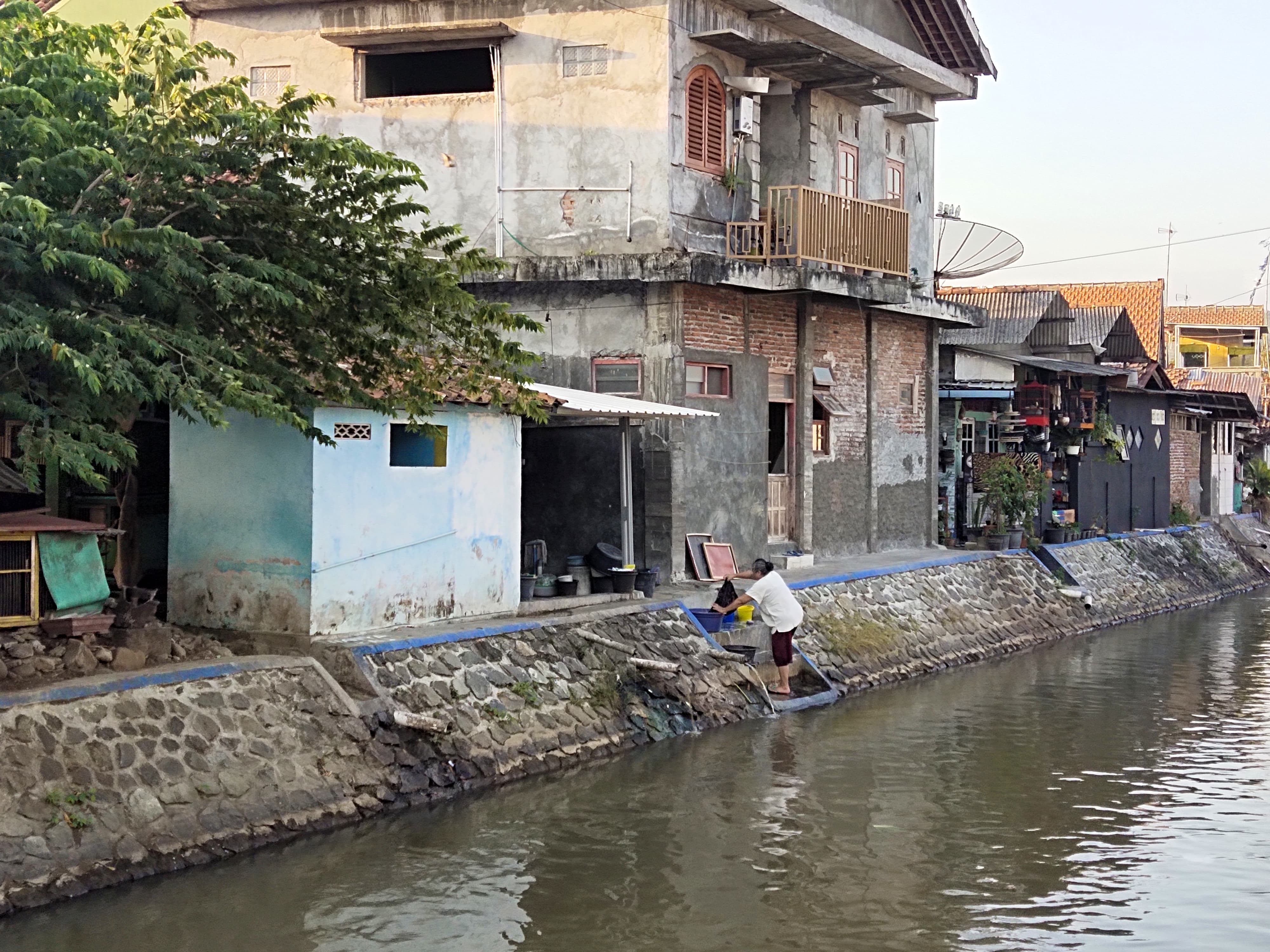MENGALIR: Salah seorang warga tengah mencuci pakaian di bantaran Sungai Kedungputri, Purworejo, Minggu (20/8). (JIHAN ARON VAHERA/RADAR PURWOREJO)