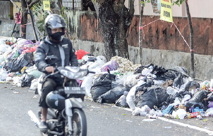 ASAL BUANG: Pengendara motor melintas di samping tumpukan sampah yang dibuang sembarangan di kawasan Jalan Kusbini, Kota Jogja (28/8).ELANG KHARISMA DEWANGGA/RADAR JOGJA