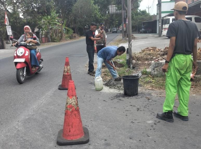 TERTIB: Petugas saat melakukan penggeseran PJU dan memasang rambu hati-hati di ruas jalan Tempel-Ngino. (Dok Dishub Sleman)