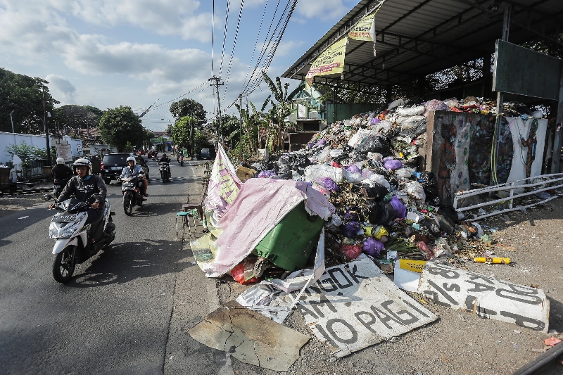 TAK TERURUS: Pengendara sepeda motor melintas di depan tumpukan sampah di Pengol, Jogja, Selasa (19/9). (ELANG KHARISMA DEWANGGA/RADAR JOGJA)