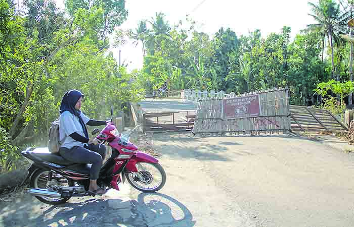 DITUTUP: Warga melintas di dekat Jembatan Pucung Growong yang rusak di Kalurahan Karangtengah, Kapanewon Imogiri, Bantul.