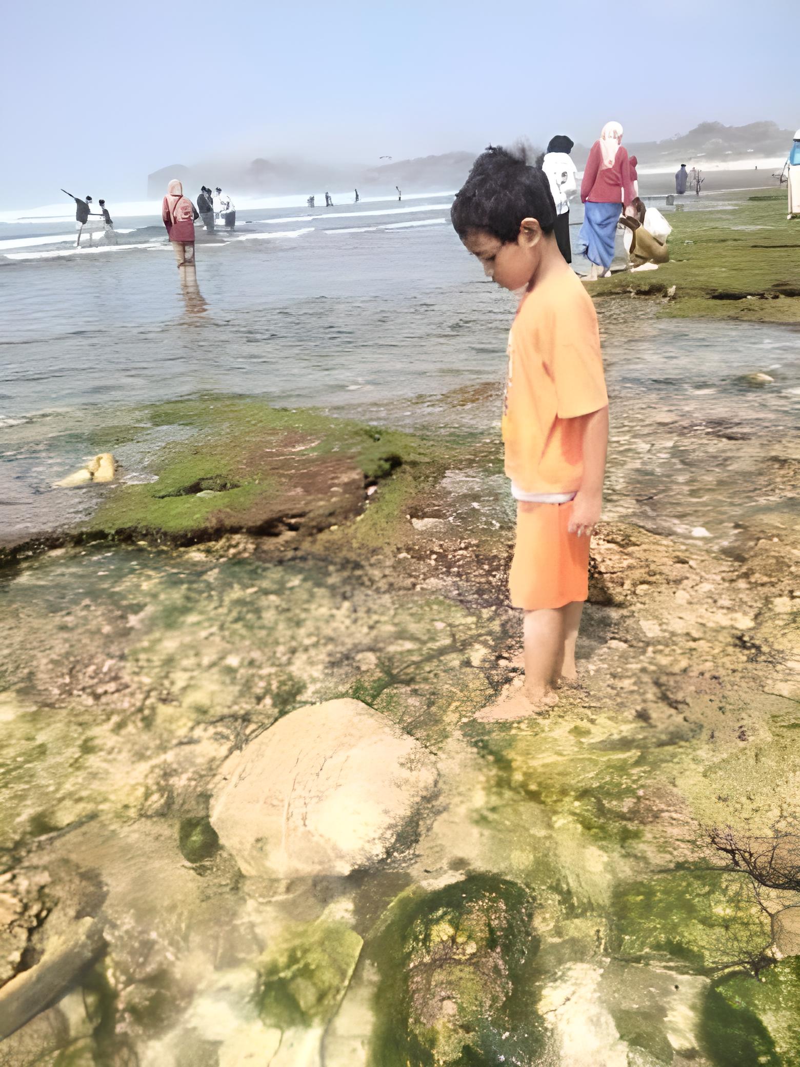 TERCEMAR - Seorang anak berdiri di antara air laut Pantai Krakal, Kemadang, Tanjungsari yang tercemar limbah cair Sabtu (7/10)