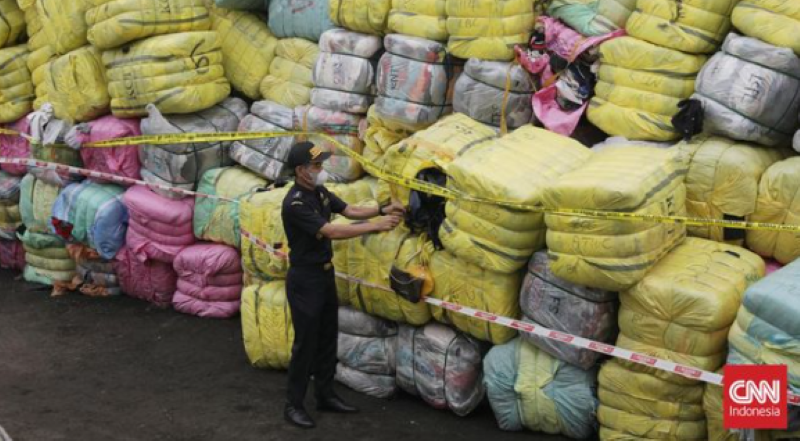 Seorang petugas tengah mengecek tumpukan pakaian bekas impor ilegal yang hendak dimusnahkan Jumat (13/10/2023) besok. (www.cnnindonesia.com)