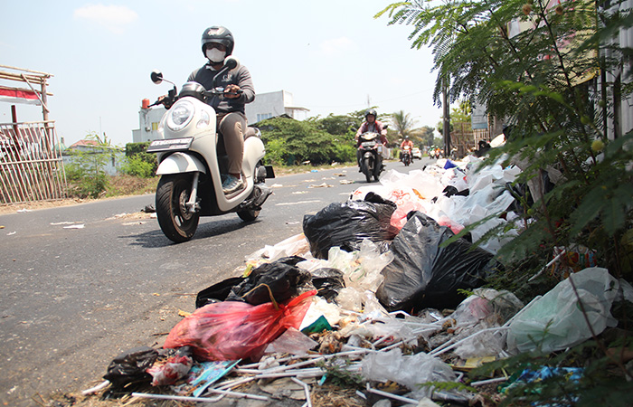 MENGGANGGU: Pengendara melintas di samping tumpukan sampah yang berserakan di Jalan Bugisan Selatan, Kalurahan Tirtonirmolo, Kasihan, Bantul.Gregorius Bramantyo/Radar Jogja