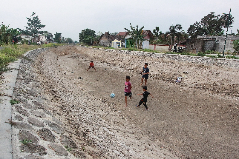KERING: Sejumlah anak bermain sepak bola di Selokan Mataram. (Guntur Aga Tirtana/Radar Jogja)