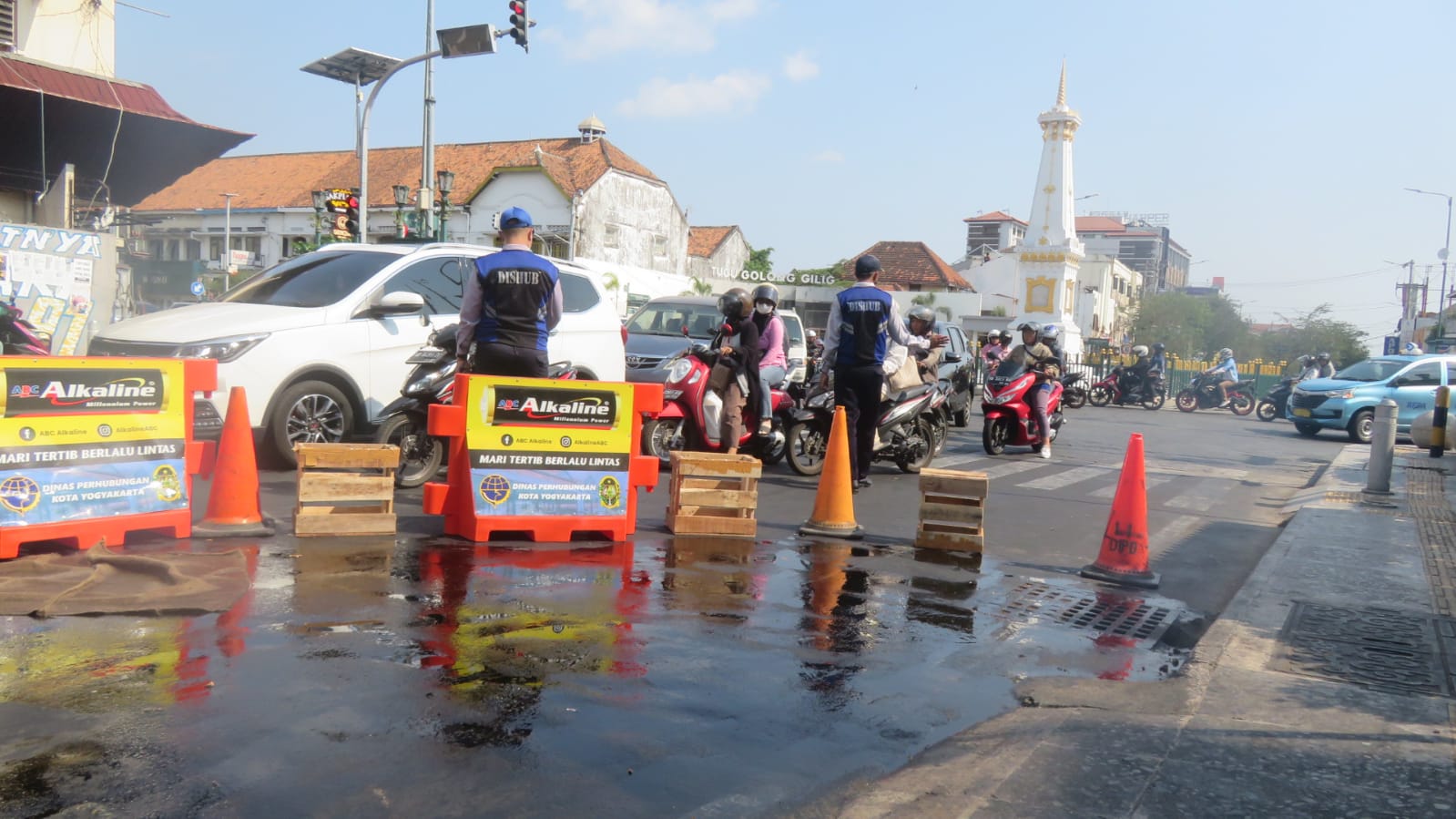 LICIN: Petugas dinas perhubungan menjaga lokasi yang licin akibat adanya minyak di dekat Tugu Pal Putih Jogja. (Dwi Agus/Radar Jogja)