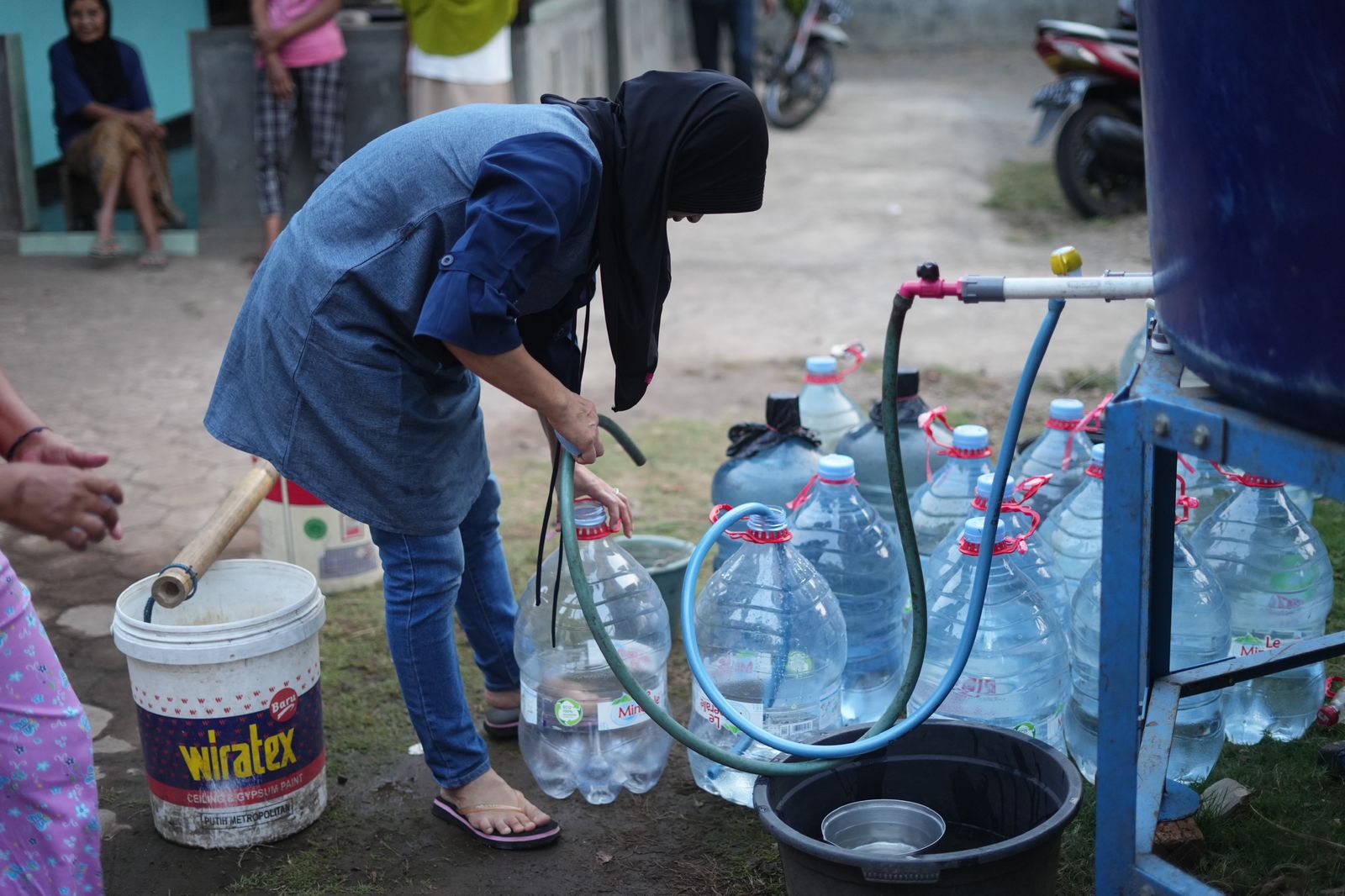 NGUCUR: Warga Tempel mengisi air dari tangki penampungan ke dalam galon Jumat (3/11/23).