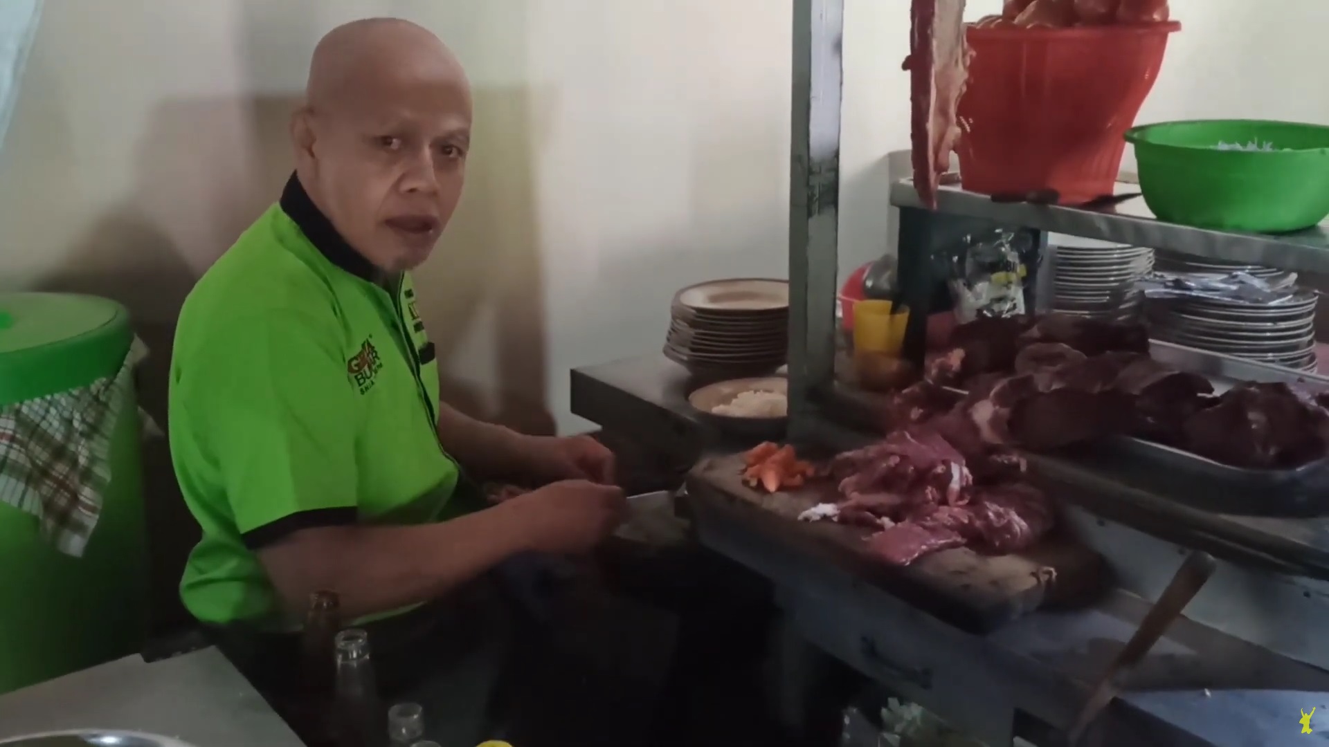 Pak Yono sedang mengiris daging kambing dengan cara unik untuk dimasak menjadi tongseng kambing.