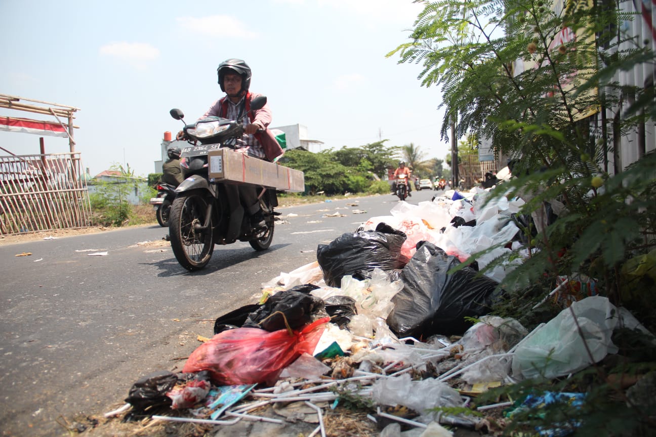 UTAMA: Pengendara melintas di samping tumpukan sampah yang berserakan di Jalan Bugisan Selatan, Kalurahan Tirtonirmolo, Kasihan, Bantul beberapa waktu lalu. (Gregorius Bramantyo/Radar Jogja)