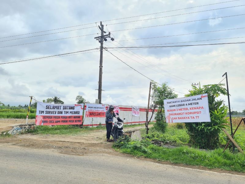 Warga Dusun Curah Lor layangkan aksi protes meminta agar jalan penghubung antardusun sekitar diperlebar dan ditinggikan. (Naila Nihayah/Radar Jogja)