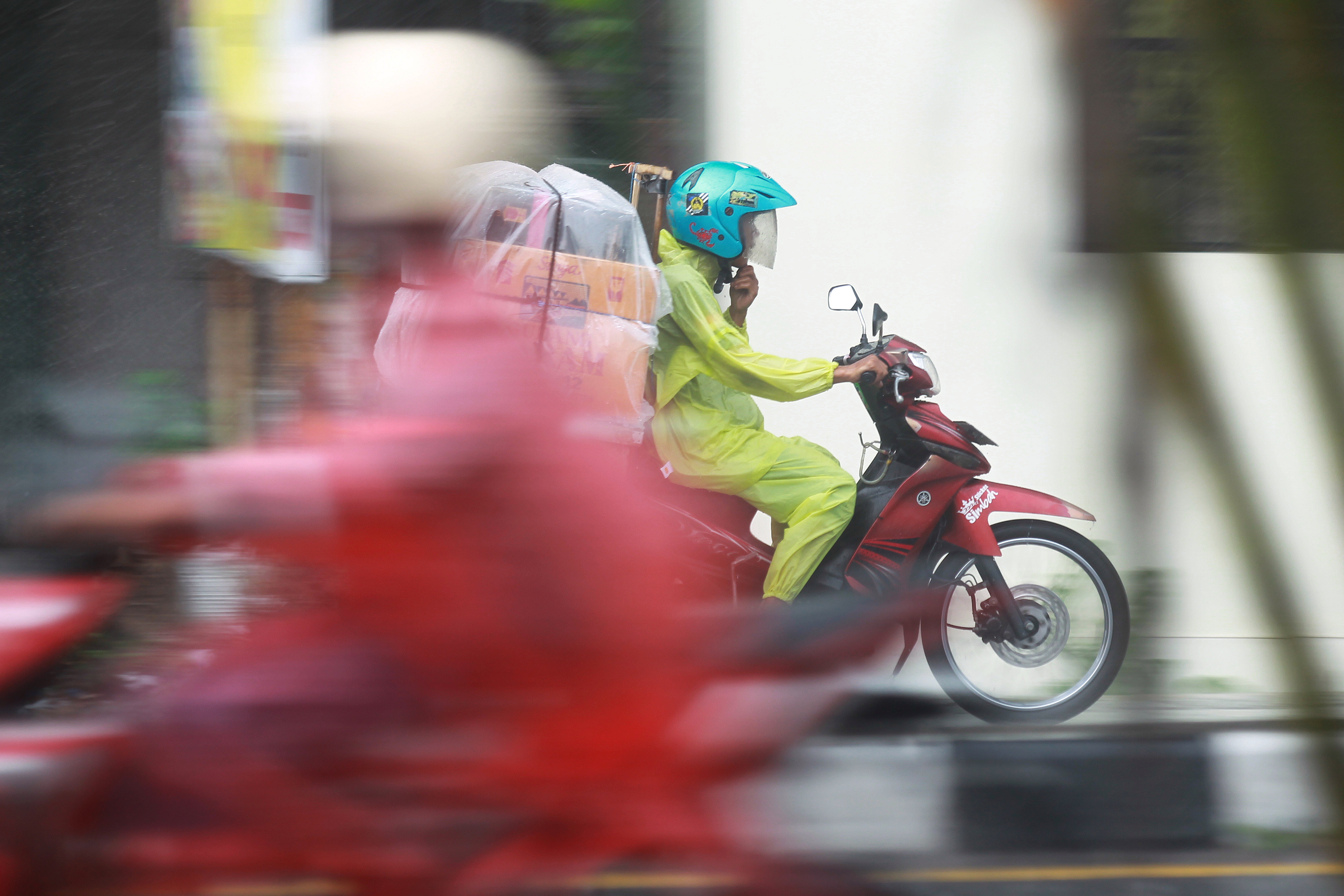 Pengendara sepeda motor menembus hujan yang mengguyur Jalan Magelang, Sleman.