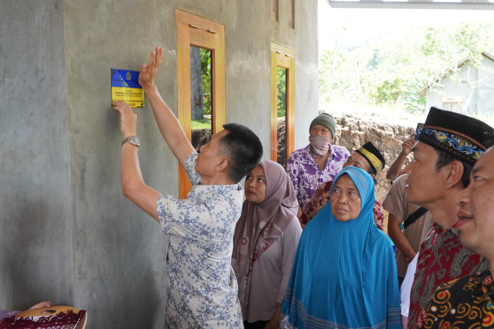 ALHAMDULILLAH - Bupati Gunungkidul Sunaryanta memasang stiker salah satu rumah ahli waris korban longsor di Blembem, Candirejo, Semin Kamis (14/12). Foto: Gunawan/Radar Jogja