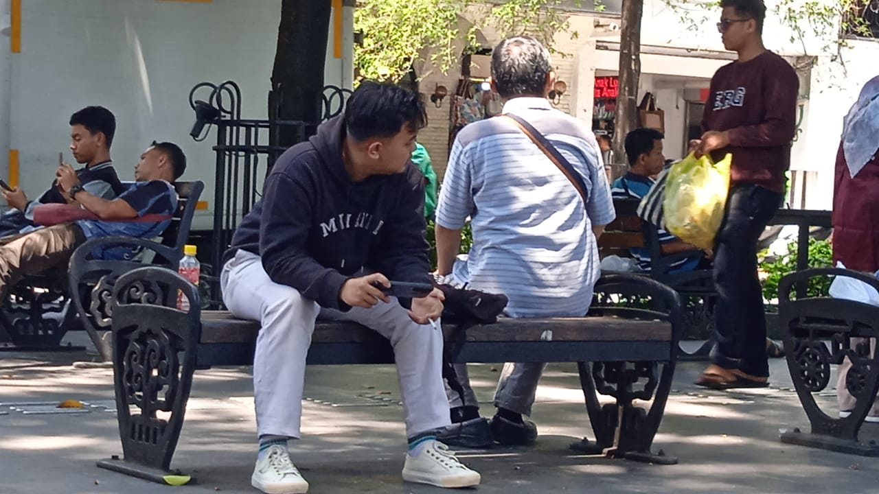 Salah seorang pengunjung Malioboro terpantau duduk sembari memegang rokok di pedestrian Jalan Malioboro, Kamis 21/12/2023. Foto: Baharuddin Kamba untuk Radar Jogja