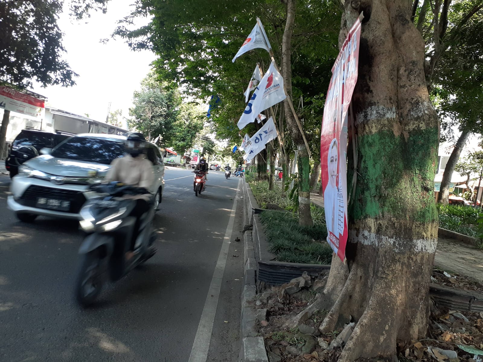 PARAH: Suasana pepohonan di Jalan KRT Pringgodiningrat yang penuh dengan bendera partai politik pada Jumat (22/12). (IWAN NURWANTO/Radar Jogja)