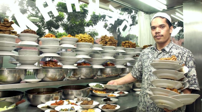 Ilustrasi seorang penjual warung makan padang tengah mendisplay  makanan dagangannya. (transfez.id)