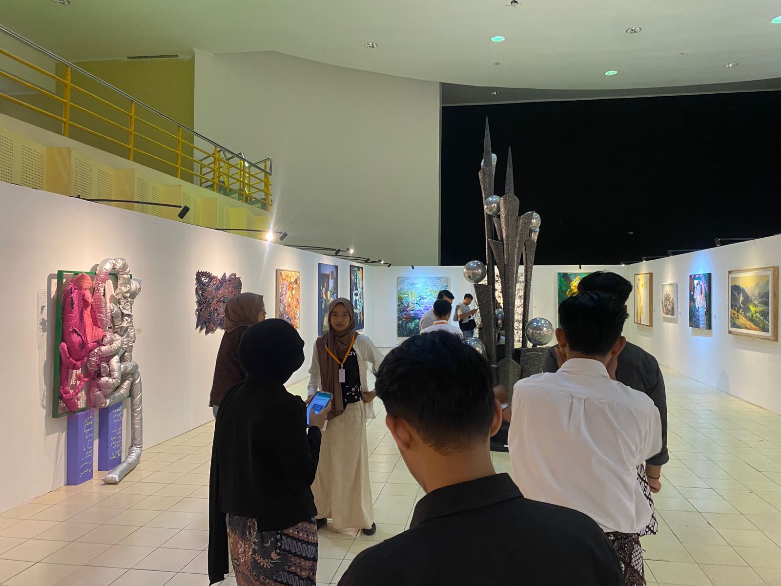 Pengunjung sedang menikmati karya rupa yang dipamerkan di Pameran Ziarah Lintas Agama, UIN SUKA.