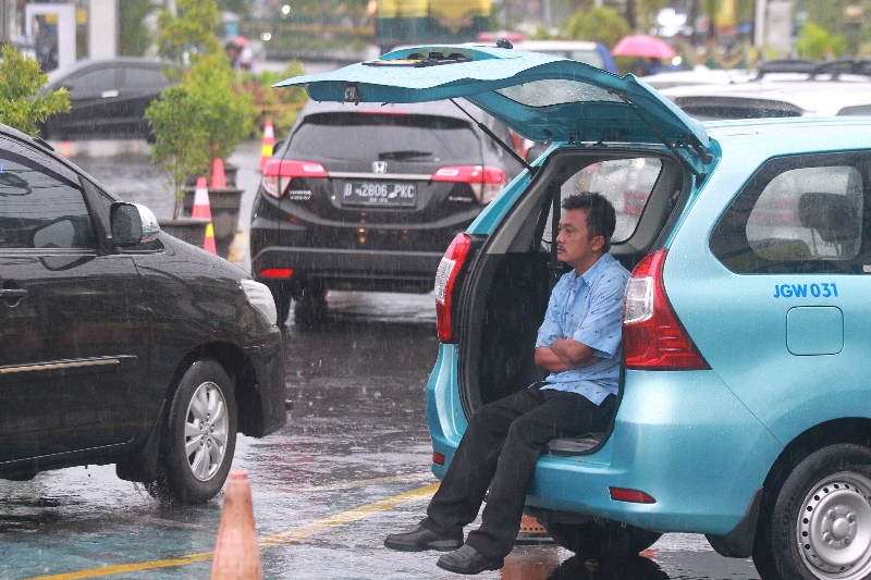 BASAH: Sopir armada taksi berteduh dari hujan saat menunggu penumpang di Kota Jogja. BMKG memprakirakan hujan potensial turun. (Guntur Aga Tirtana/Radar Jogja)