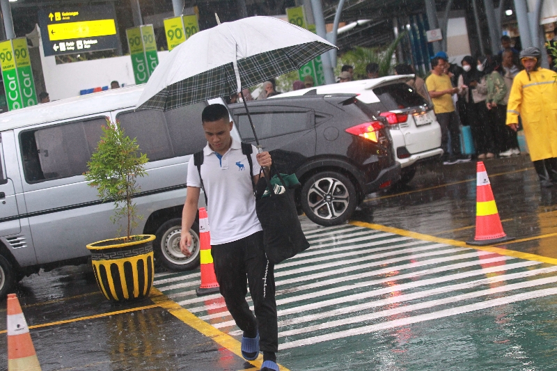 BASAH: Warga memakai payung untuk menghindari air hujan.