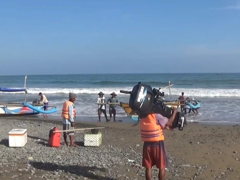 MELAUT : Nelayan di pesisir selatan Kebumen memanggul mesin perahu sebelum pergi mencari ikan.
