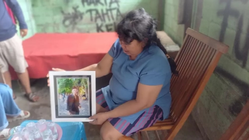 PEKERJA KERAS: Putu Suartini, ibu kandung Adhi Putra Krisnawan, memegang foto anaknya yang telah tiada akibat pengeroyokan sadis di Dalung, Badung.