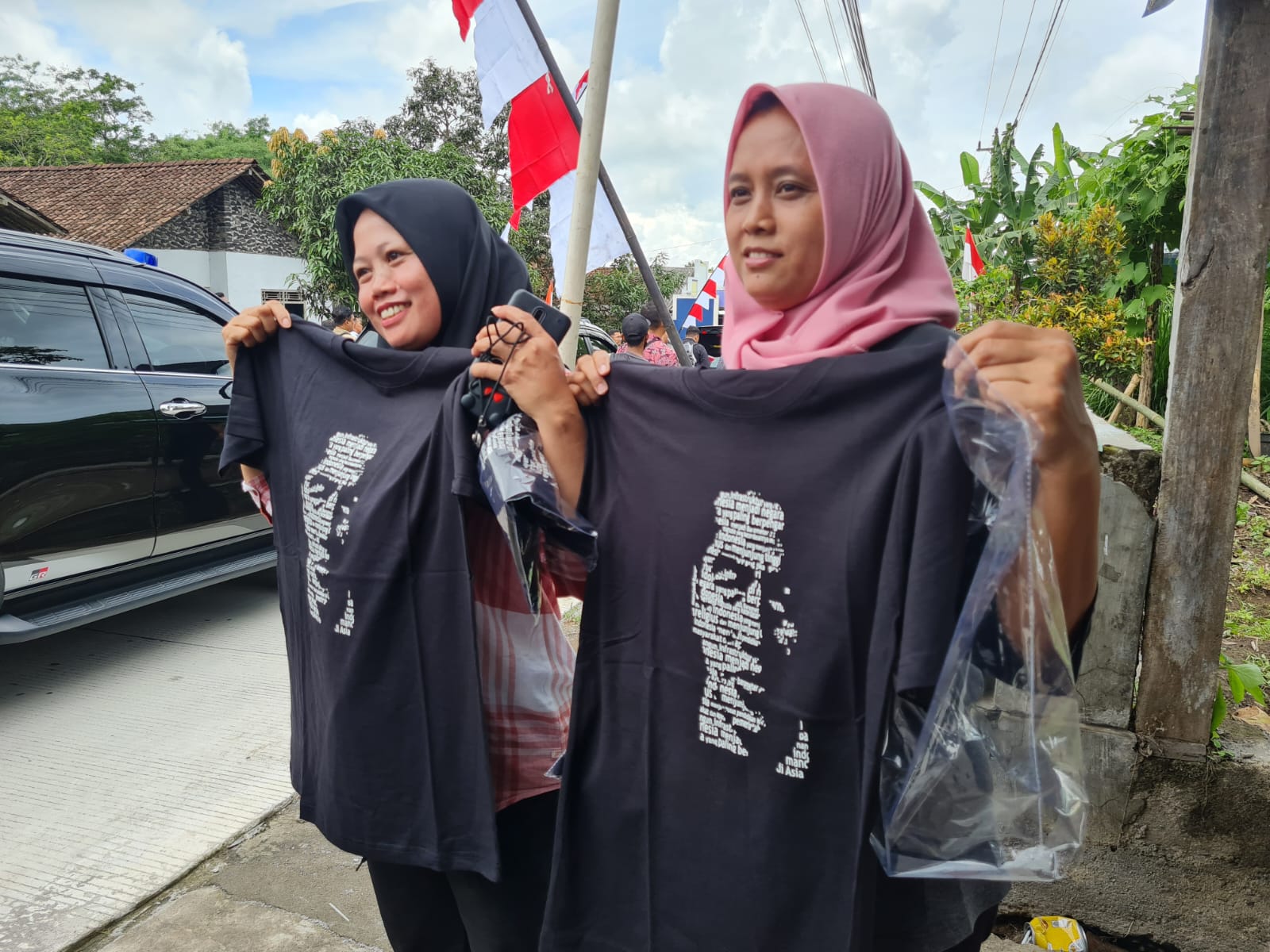 SEMRINGAH: Dua warga Kecamatan Dukun memperlihatkan kaus yang diperoleh dari Presiden Jokowi. Mereka sudah menanti kedatangannya sejak pukul 09.30.