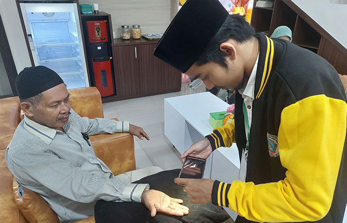 PELAYANAN: Kasiran, jemaah calon haji dari Karangwuni sedang melakukan pemindaian sidik 10 jari, dibantu oleh petugas untuk kepentingan rekam biometrik.Anom Bagaskoro/Radar Jogja