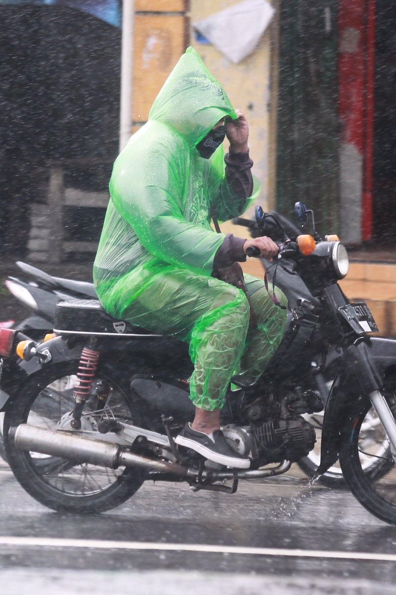 BASAH: Pengendara sepeda motor mengenakan mantol saat turun hujan di Yogyakarta.