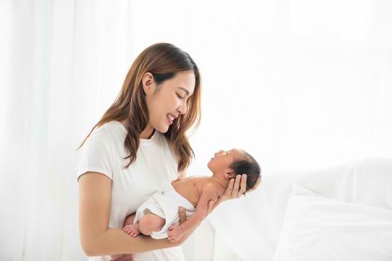 Ilustrasi seorang ibu sedang menidurkan bayinya.