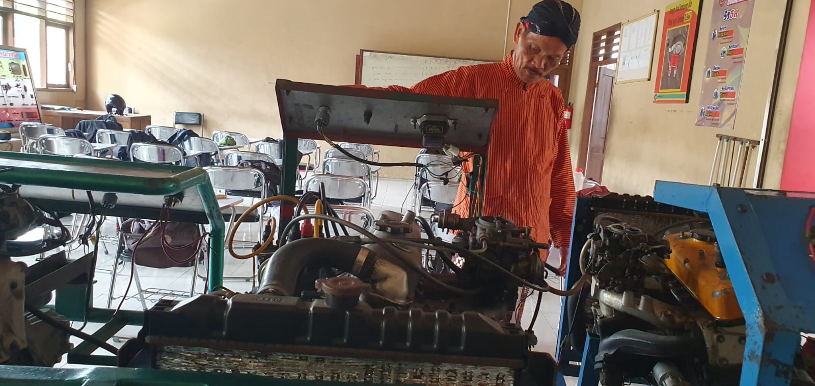 BERKARYA - Guru kesiswaan SMKN 2 Wonosari Mujiyono berpose dengan peserta didik di ruang otomotif Rabu (7/2/2024)
