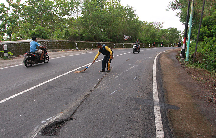 Warga membersihkan jalan yang menjadi lokasi kecelakaan bus pariwisata terguling di Jalan Imogiri-Dlingo.GUNTUR AGA TIRTANA/RADAR JOGJA