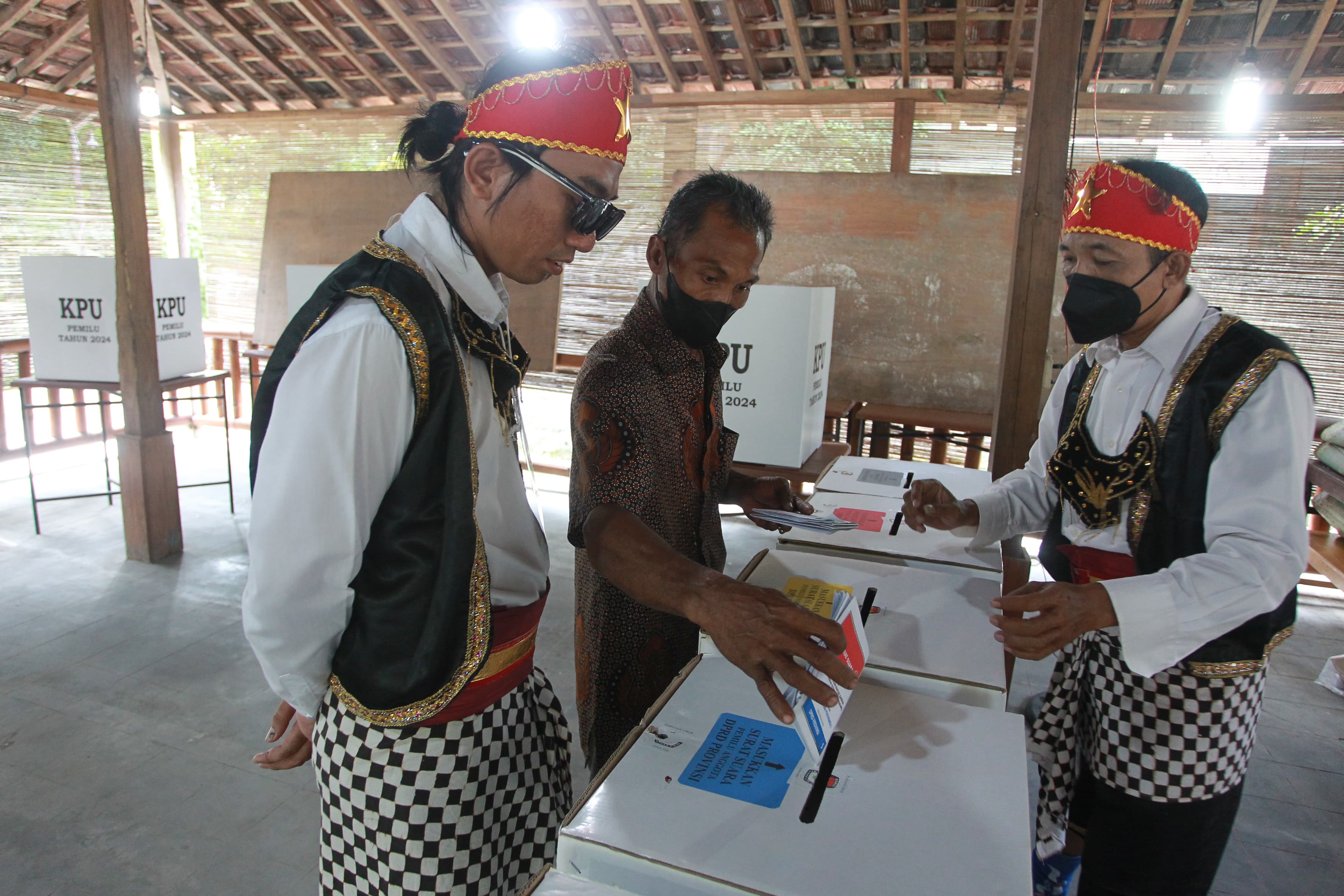 KHAS: Petugas KPPS berkostum penari badui membantu warga memasukkan surat suara Pemilu 2024 di TPS 102 Maguwoharjo, Sleman, DIY, Rabu (14/2).