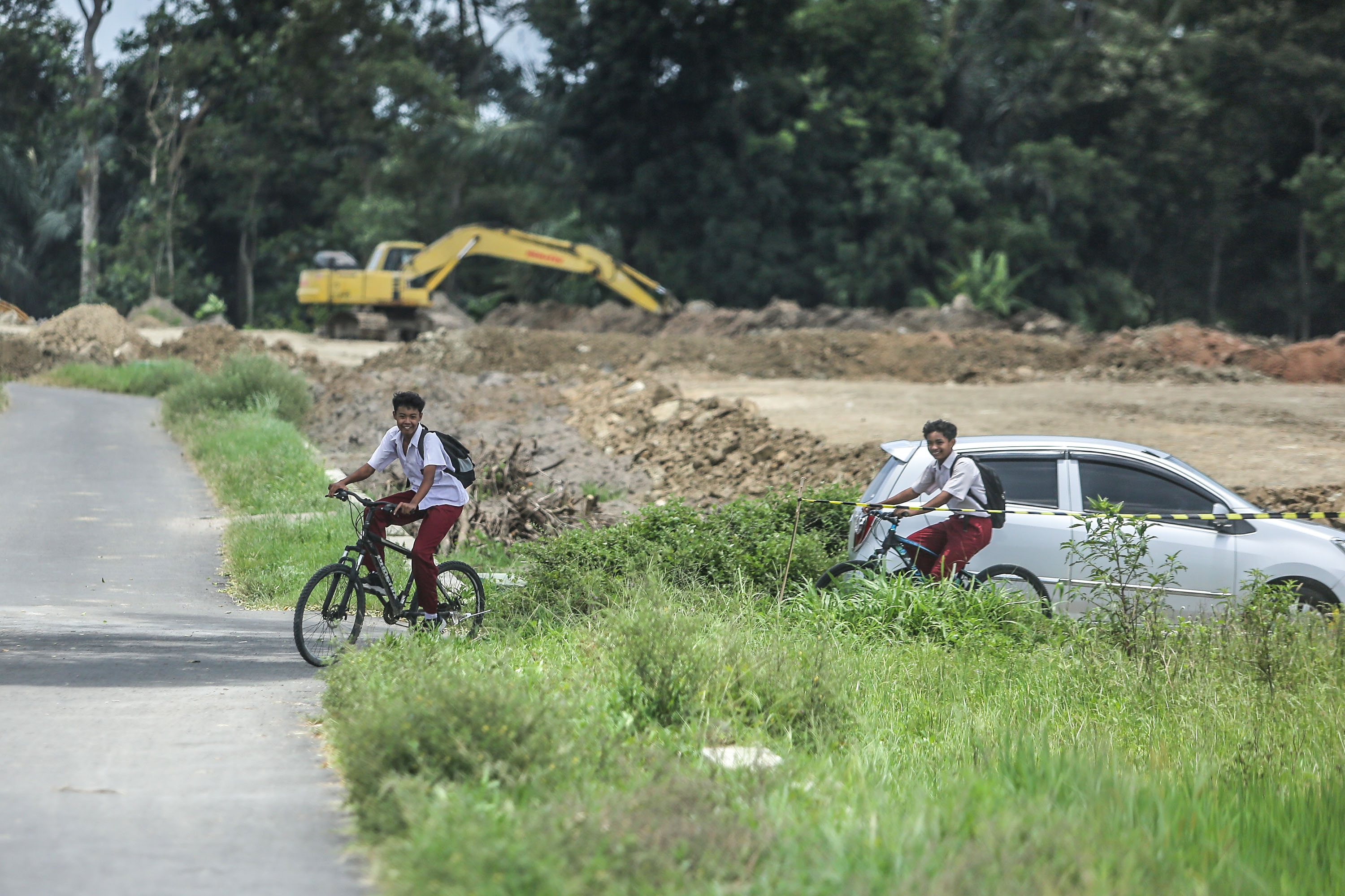 DEKAT: Warga melintas berlatar pengerjaan proyek tol di kawasan Selomartani, Kalasan, Sleman, Kamis (22/2).