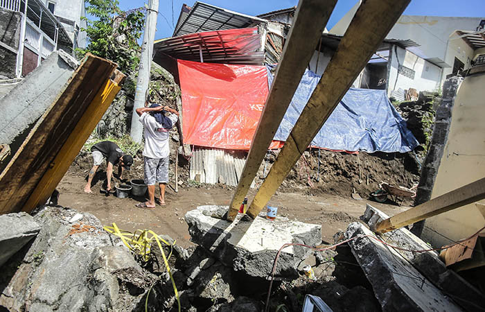 Warga gotong-royong membersihkan puing talud yang longsor saat hujan deras Minggu (25/2) lalu di Kawasan Karangasem, Condongcatur, Depok, Sleman, Senin (26/2).
