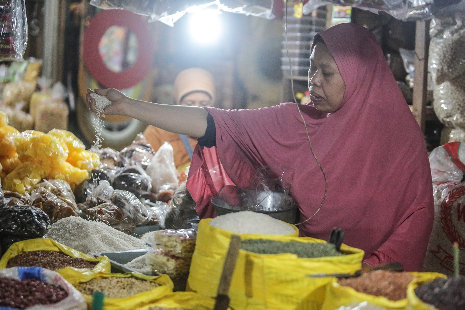 Menthuk, pedagang bahan pokok di Pasar Beringharjo, Jogja melayani pembeli beras, Selasa (27/2/2024).