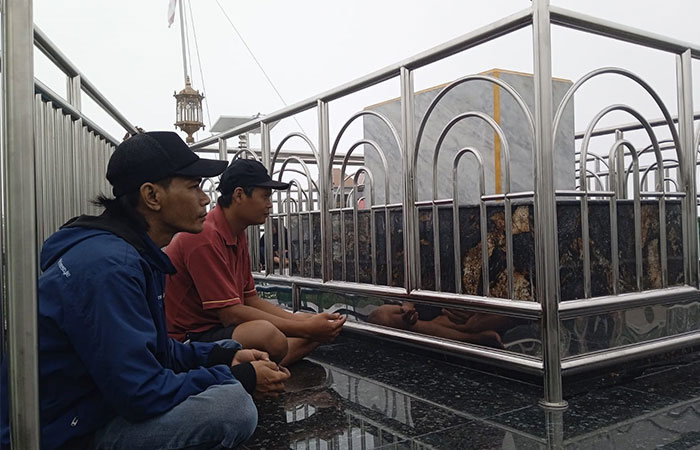 KHUSYUK: Peziarah Dwi Fajar dan Armanto dari Kulon Progo dan Purworejo melantunkan doa di makam Syekh Jumadil Qubro, puncak Bukit Turgo, Pakem, Sleman akhir Februari lalu.