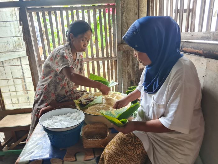 TELATEN: Usai ditumbuk, Poningsih bersama Kasmirah mulai membungkus jemunak dengan daun pisang. Di dalamnya dilengkapi parutan kelapa dan gula merah cair.