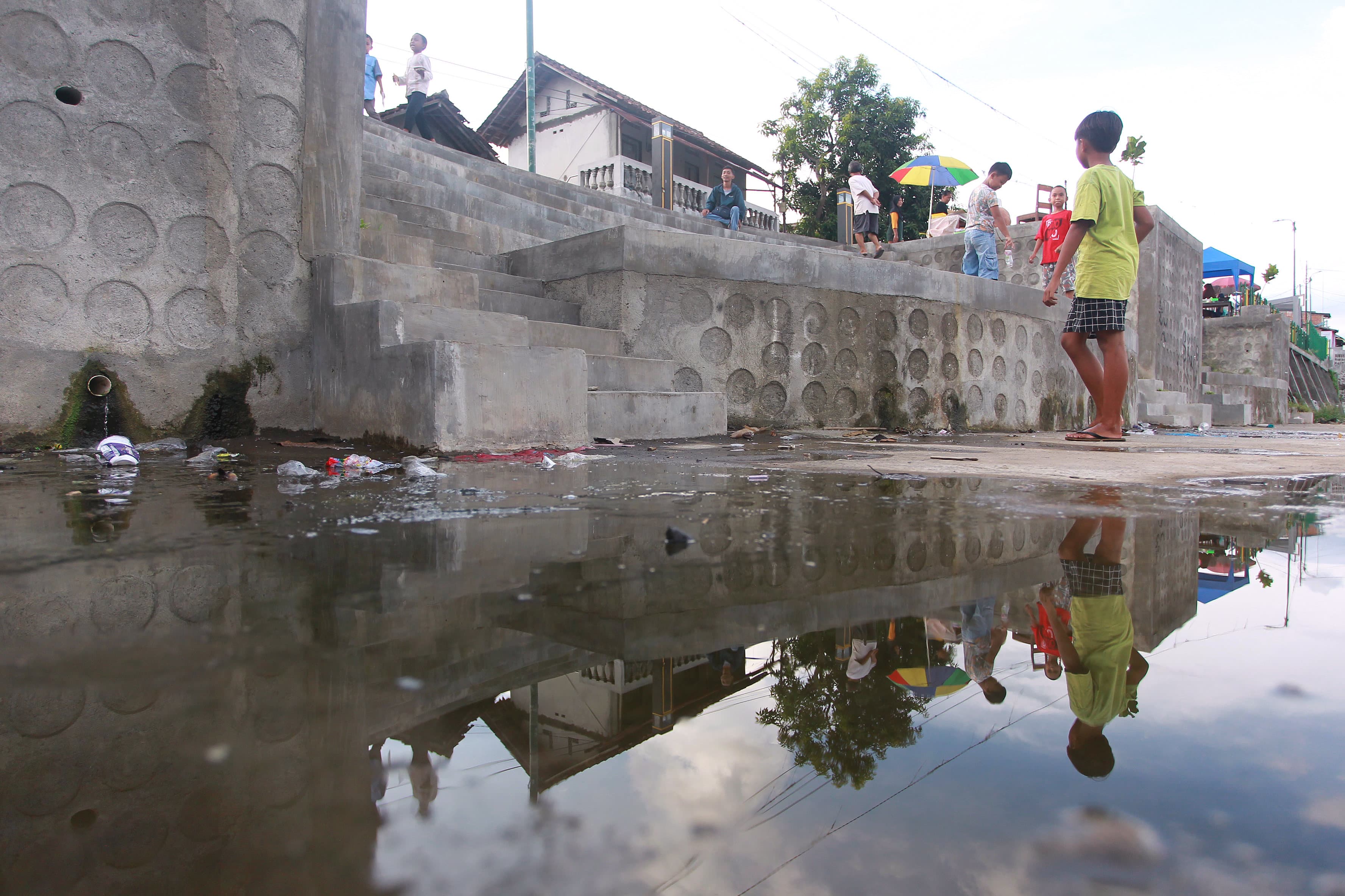 DOLAN: Sejumlah anak bermain di dekat genangan air yang dapat menjadi berkembangnya nyamuk aedes aegypti yang menyebabkan demam berdarah dengue (DBD).